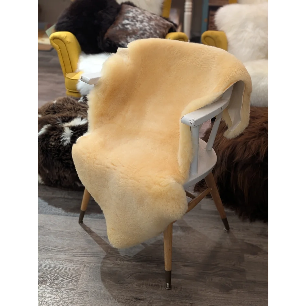 Cream-colored extra large medical sheepskin throw draped over white wooden chair by angus oliver