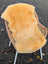 Warm golden yellow medical sheepskin rug draped over wicker chair by angus oliver washable medical sheepskins