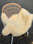 Cream-colored naturally spotted medical sheepskin throw draped over wicker chair washable and soft