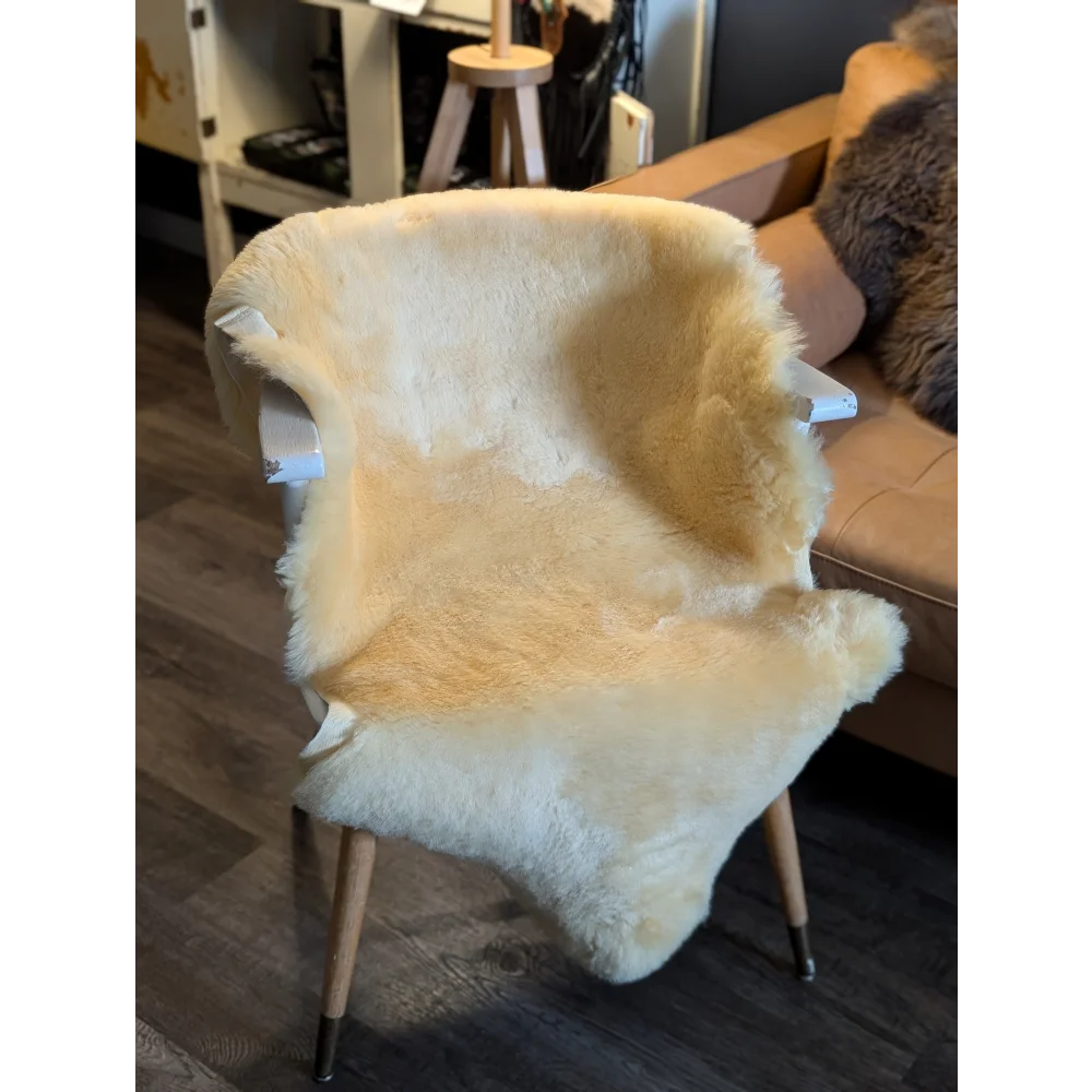 Cream-colored medical sheepskin chair cover draped over modern wooden armchair by angus oliver medium medical sheepskin