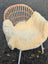 Cream-colored naturally spotted medical sheepskin blanket draped over wicker chair washable and soft