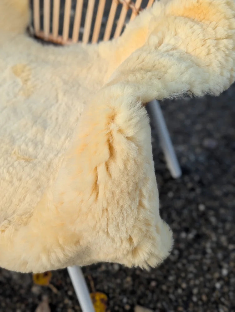 Cream-colored medical sheepskin chair cover with soft fluffy texture and naturally spotted washable material