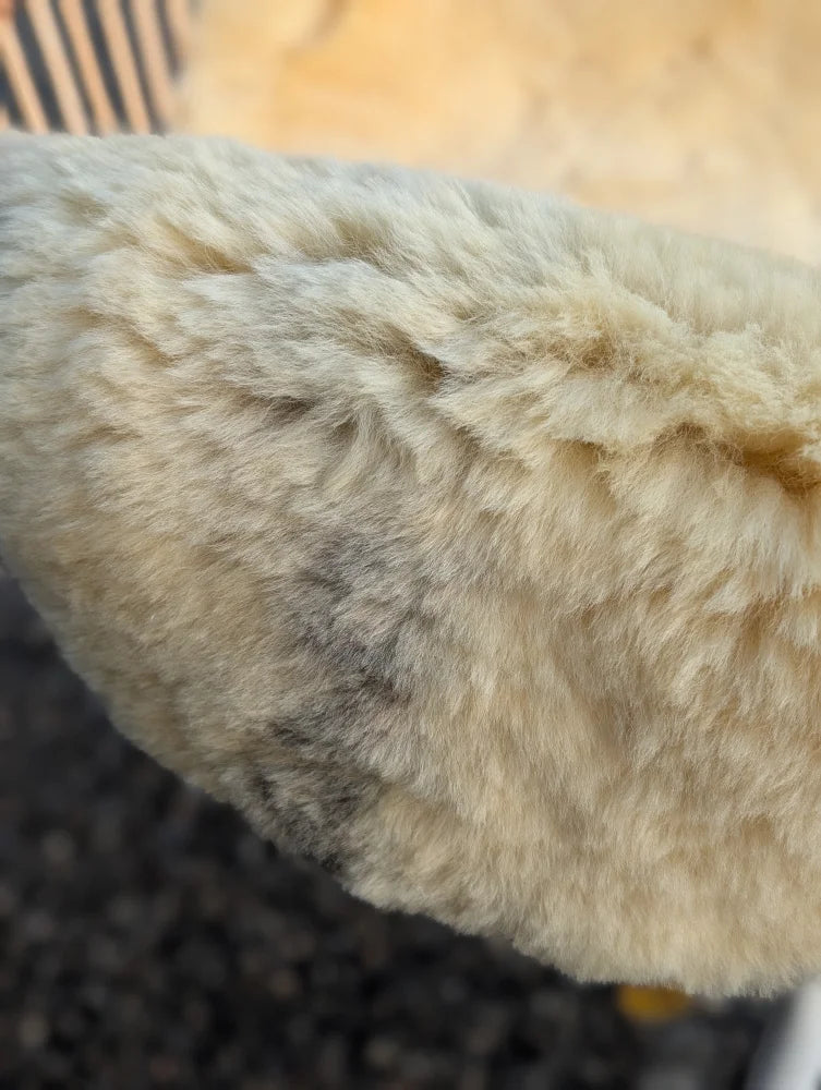 Cream-colored plush faux fur ear warmer with soft texture and subtle gray patches on medically washable naturally spotted medical sheepskin