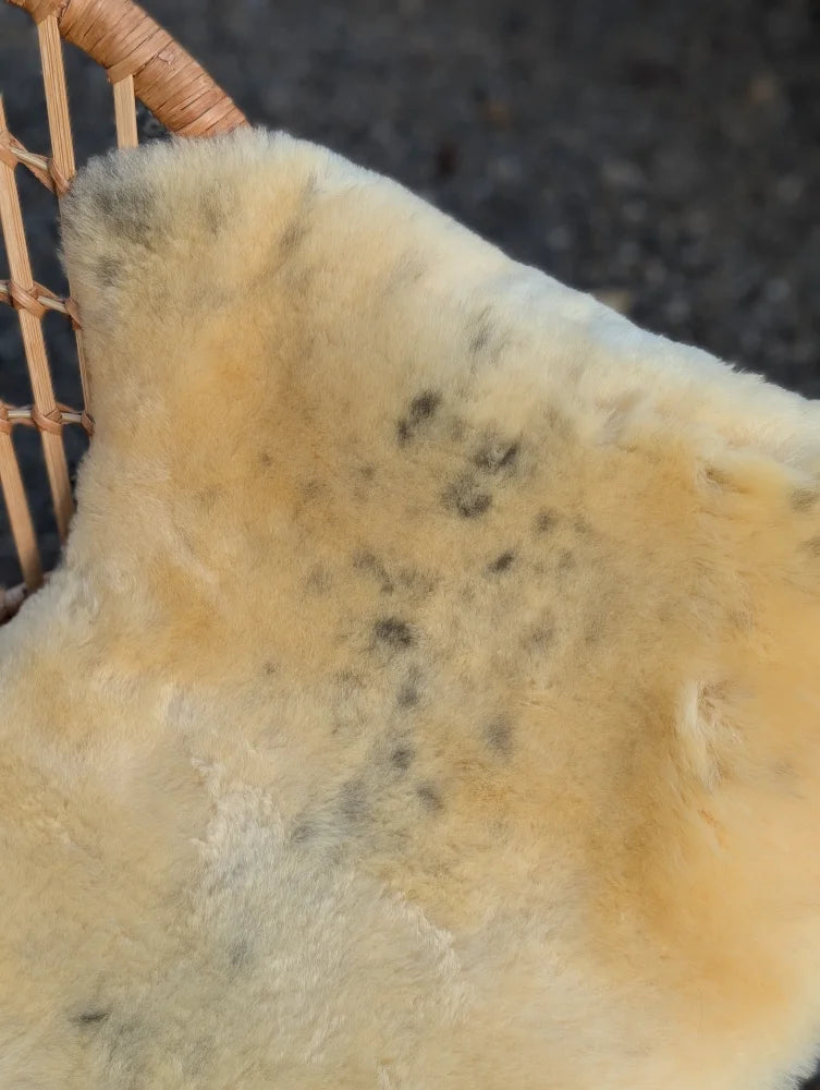 Cream-colored medical sheepskin rug with natural soft fur and subtle dark speckles naturally spotted and washable