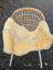 A soft creamy beige naturally spotted medical sheepskin blanket draped over a wicker chair with white metal legs