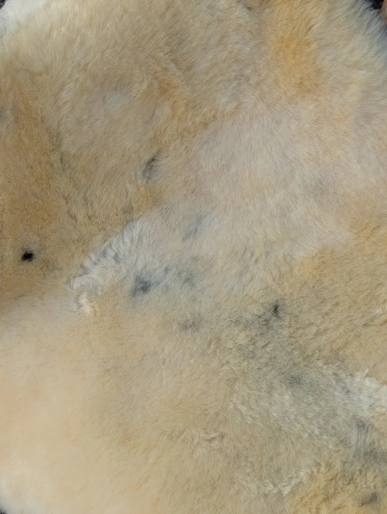Cream-colored fluffy medical sheepskin rug with natural tone variations and subtle dark speckles naturally spotted