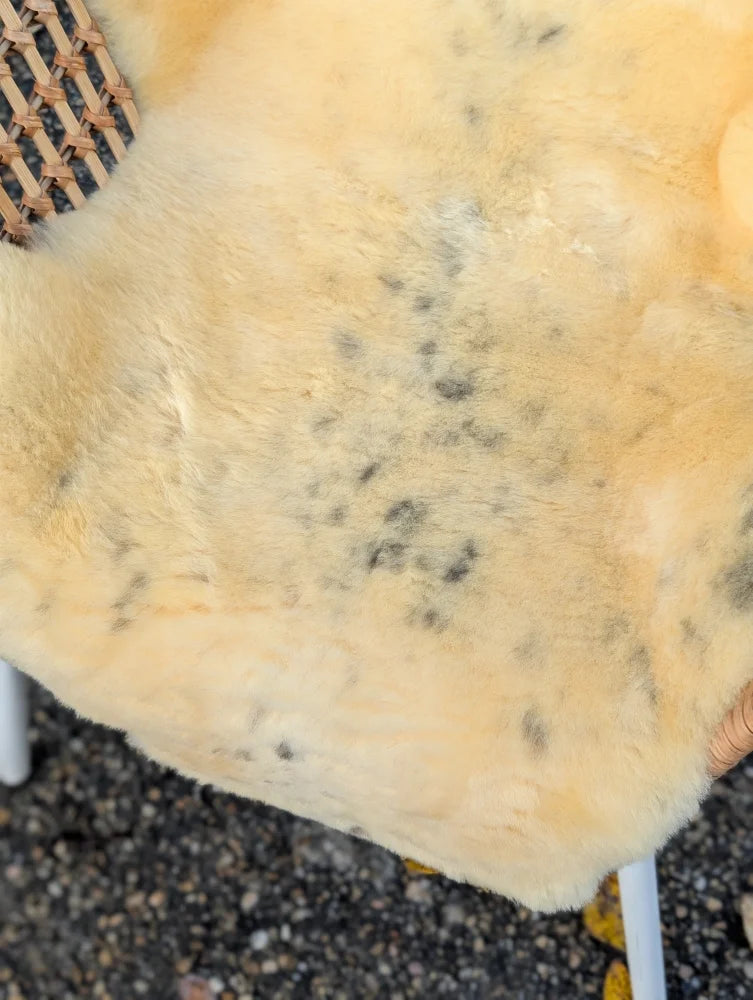 Cream-colored naturally spotted medical sheepskin rug with soft fluffy texture and dark gray speckles washable med26 model