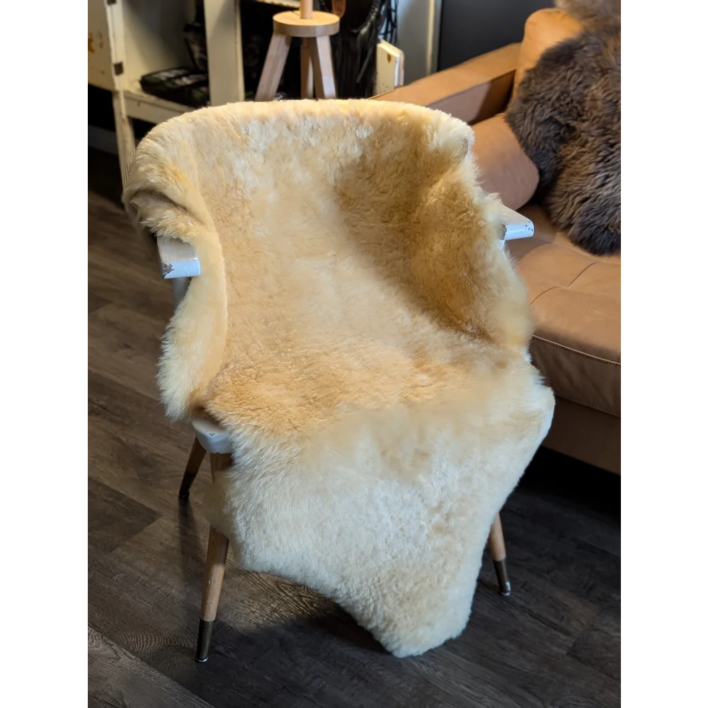 Cream-colored extra large medical sheepskin throw draped over white wooden chair by angus oliver