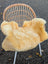 Soft golden-yellow washable medical sheepskin blanket draped over wicker chair by angus oliver british sheepskins