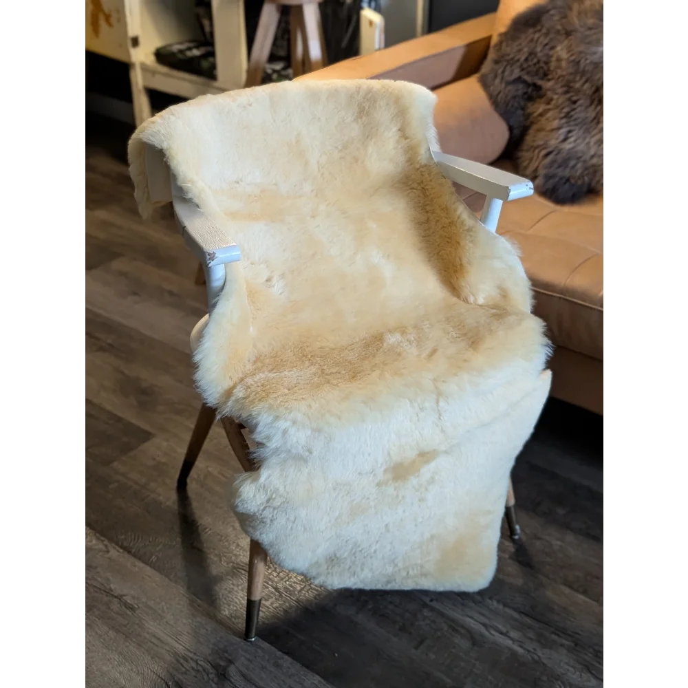 Cream-colored extra large medical sheepskin throw draped over white wooden chair with tapered legs by angus oliver