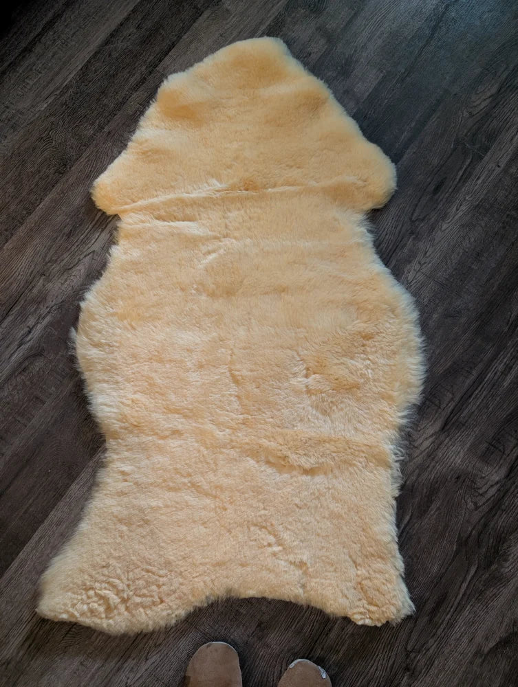 A soft creamy beige extra large medical sheepskin rug with plush natural fur texture by angus oliver