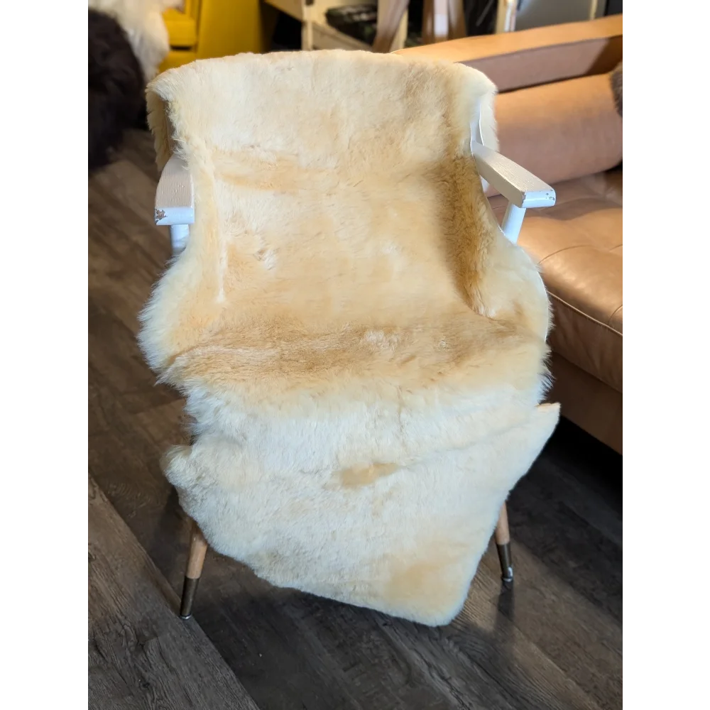 Cream-colored extra large medical sheepskin throw draped over white wooden chair with metal legs by angus oliver