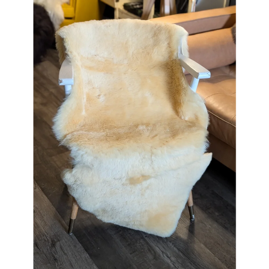 Cream-colored extra large medical sheepskin throw draped over white wooden chair with metal legs by angus oliver