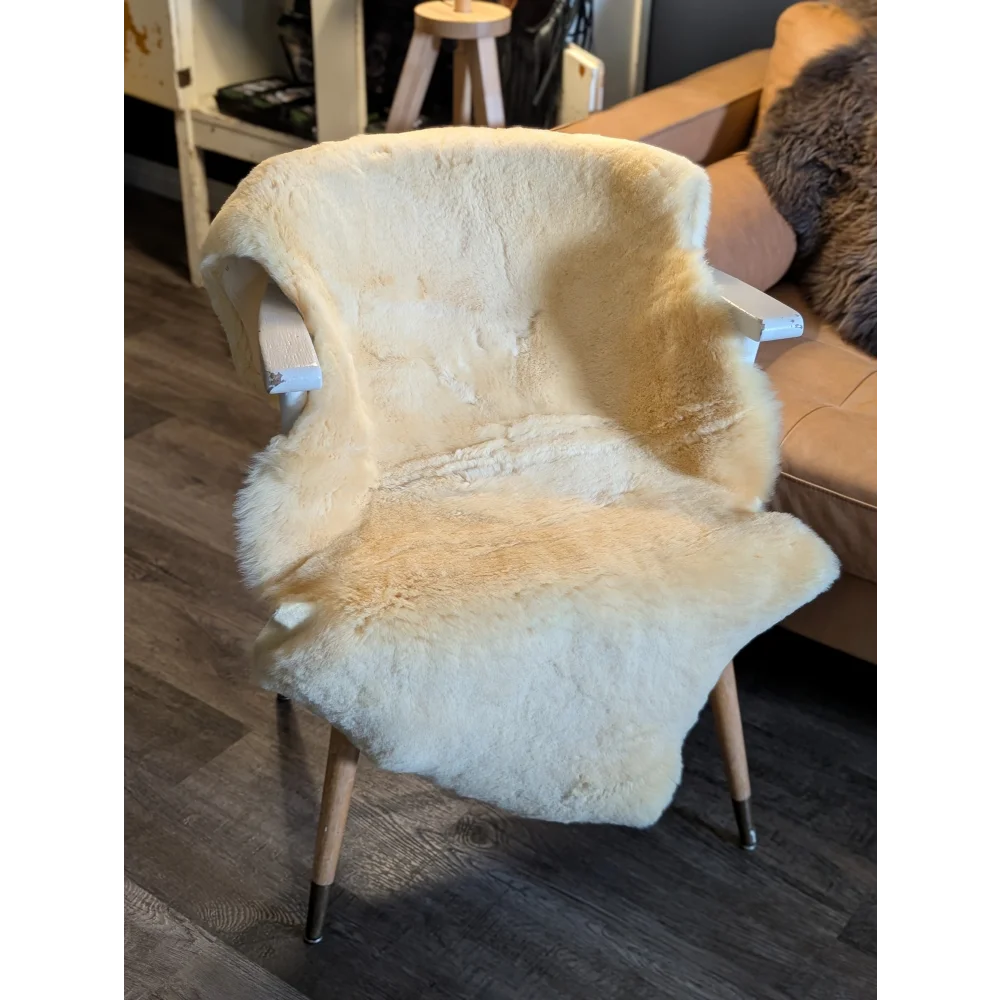 A cozy cream medical sheepskin throw draped over a wooden chair from angus oliver medium medical sheepskin line