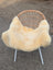 A soft creamy off-white medical sheepskin throw draped over a wicker chair with white metal legs naturally spotted
