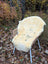 Cream-colored naturally spotted medical sheepskin rug draped over a wicker chair for washable comfort