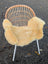 A cozy light beige washable medical sheepskin blanket draped over a modern rattan chair by angus oliver british sheepskins