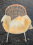 A cozy cream-colored washable medical sheepskin blanket draped over a wicker chair by angus oliver british sheepskins
