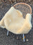 Cream-colored washable medical sheepskin blanket draped over wicker chair featuring soft sheepskin material