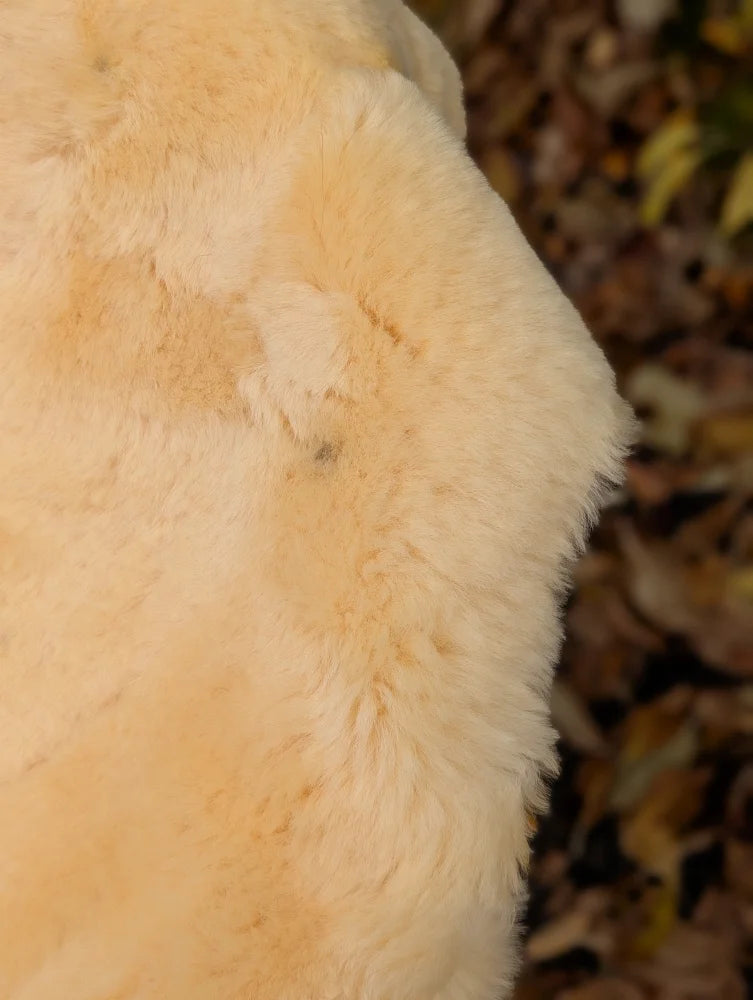 Cream-colored plush faux fur blanket with soft texture in a washable medical sheepskin naturally spotted design