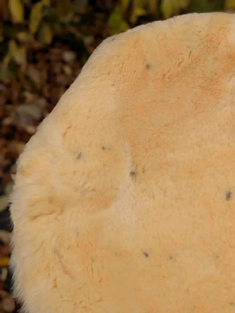A soft pale yellowish orange fuzzy medical sheepskin with naturally spotted texture in 52.5 x 33 washable size