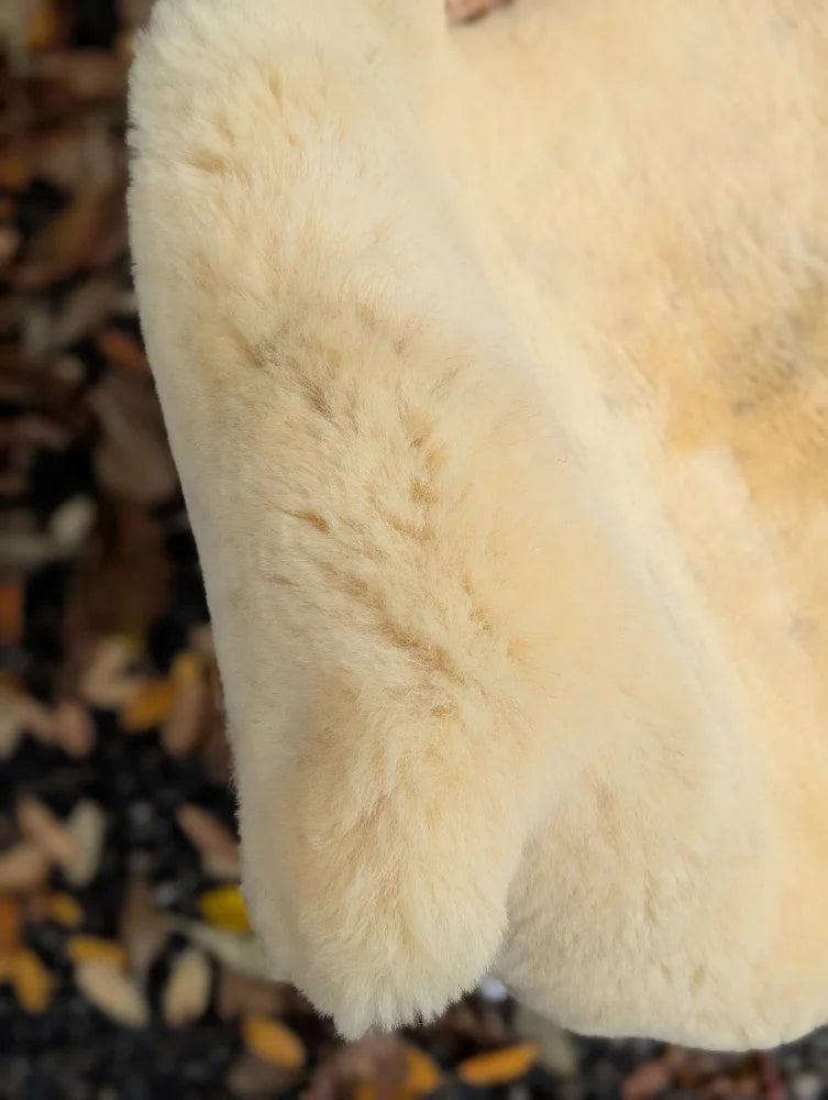 Cream-colored plush faux fur coat with soft fluffy texture made from washable naturally spotted medical sheepskin