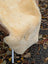 Cream-colored medical sheepskin rug with naturally spotted soft fluffy texture washable 50 x 33 inches