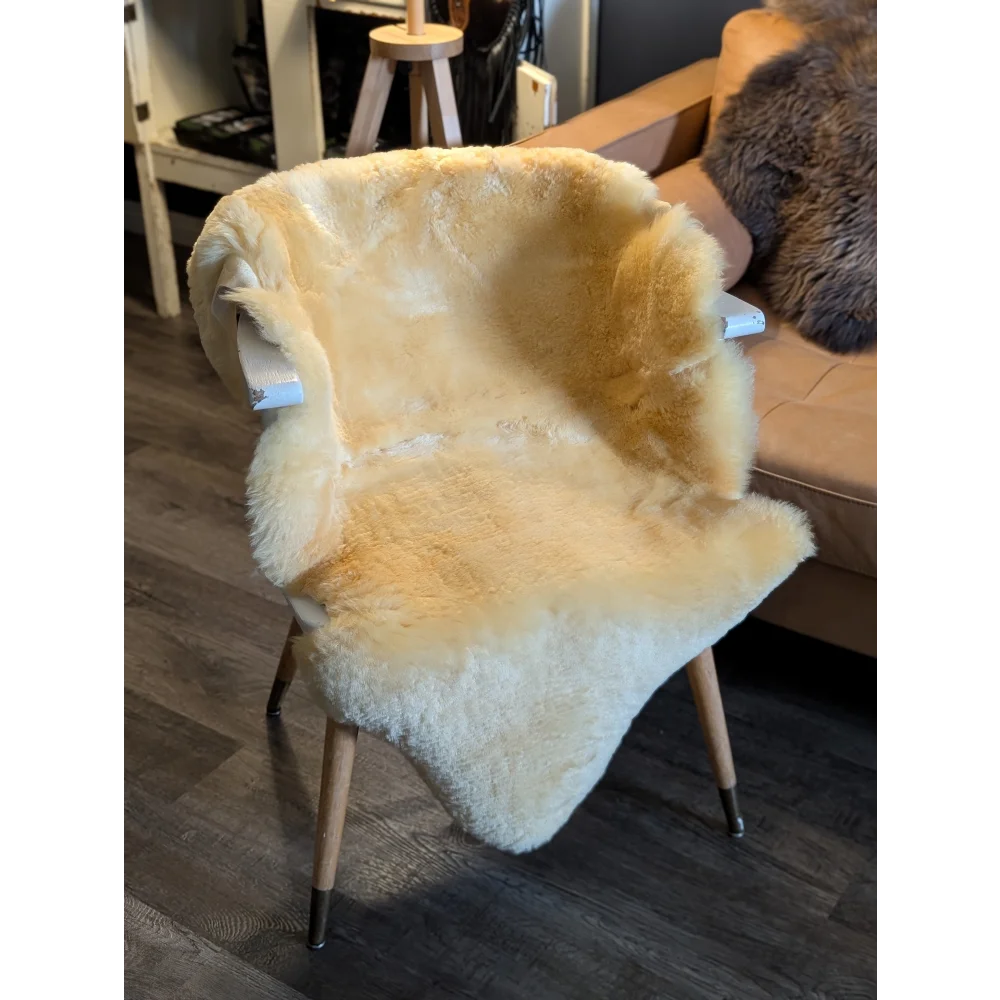 A cozy cream-colored medical sheepskin chair with wooden legs and metal caps from angus oliver medium medical sheepskin