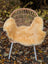 A cozy light golden medical sheepskin throw from angus oliver draped over a woven wicker chair with white metal legs