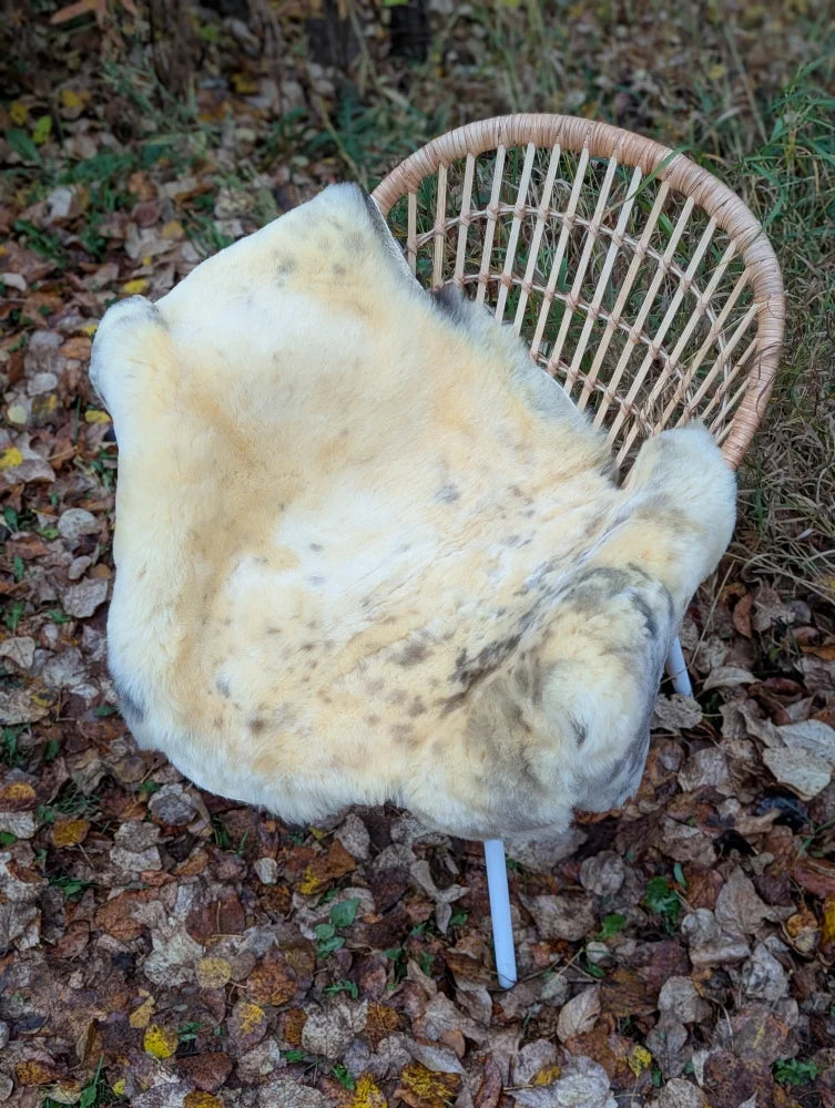 A cream-colored washable medical sheepskin rug with natural fur texture and naturally spotted grayish-brown speckles