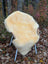 Cream-colored medical sheepskin naturally spotted draped over chair with light blue metal legs and woven wooden armrests