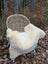 Cream-colored naturally spotted medical sheepskin blanket draped over wicker chair washable and soft