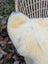 Cream-colored plush fur ear of a naturally spotted medical sheepskin washable medical sheepskins product close-up