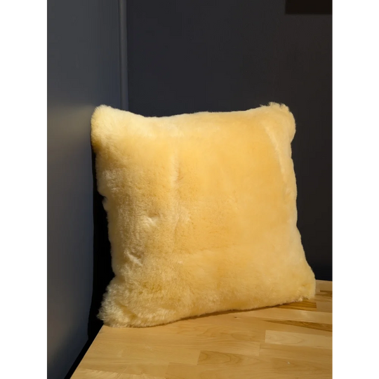 Cream-colored medical sheepskin cushion with soft fluffy texture and natural fur edges for comfort use