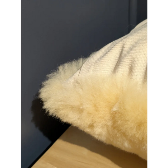 Cream-colored medical sheepskin cushion with plush fluffy sheepskin trim for cozy cushion cover comfort