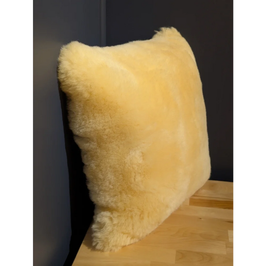 Cream-colored medical sheepskin cushion with soft fluffy texture and natural fur edges for comfort and support