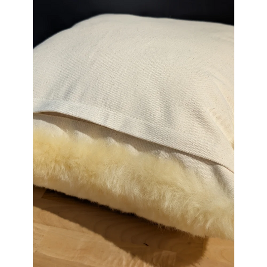 Cream-colored medical sheepskin cushion with soft fluffy interior and textured linen cushion cover for comfort