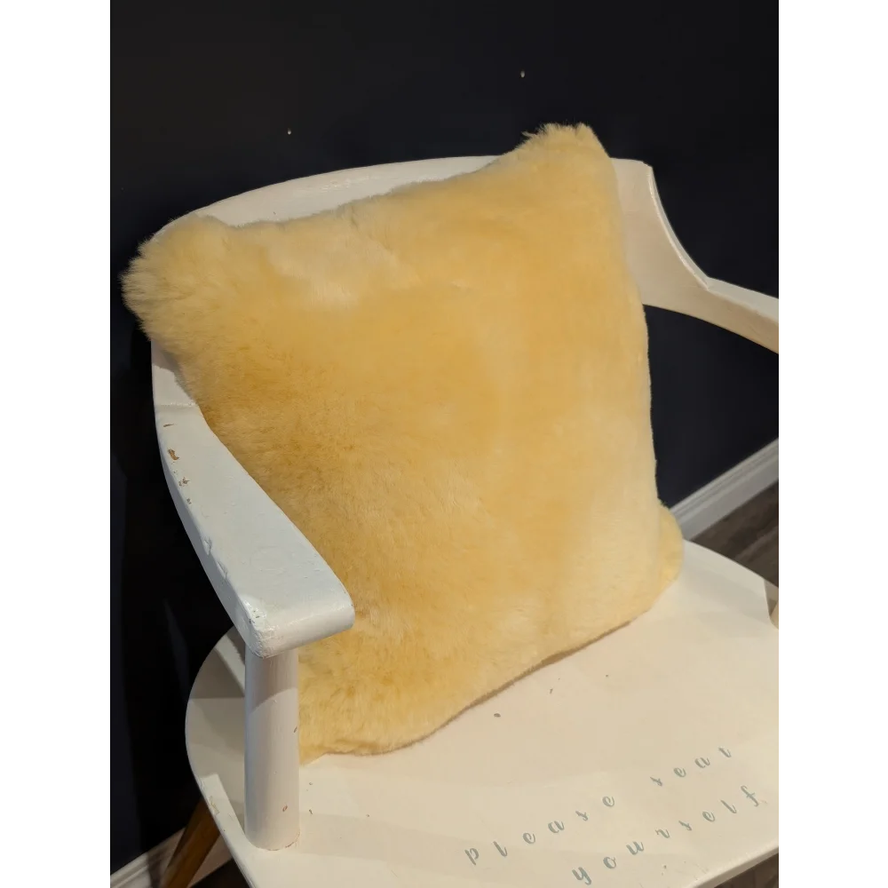 A soft golden-yellow medical sheepskin cushion cover resting on a white wooden chair for comfort and support
