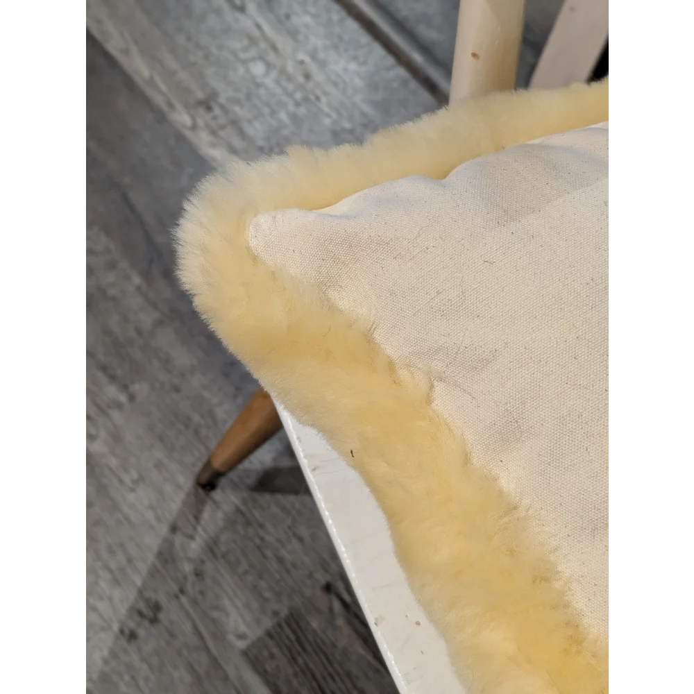 Cream-colored medical sheepskin cushion with soft fluffy yellow sheepskin trim for comfort and support