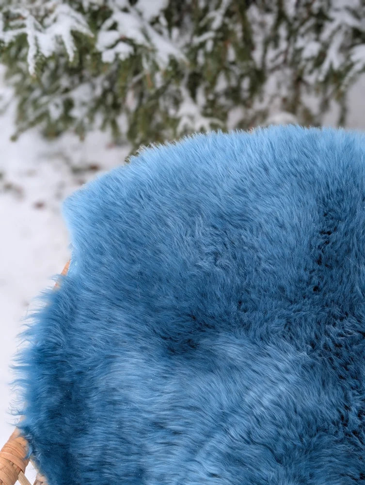 A plush vibrant blue merino sheepskin throw blanket with soft fluffy texture perfect for mid october coziness