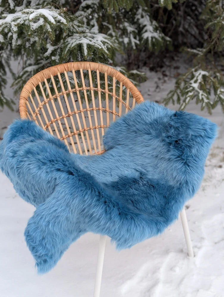 A plush blue merino sheepskin throw draped over a wicker chair perfect for cozy mid october warmth
