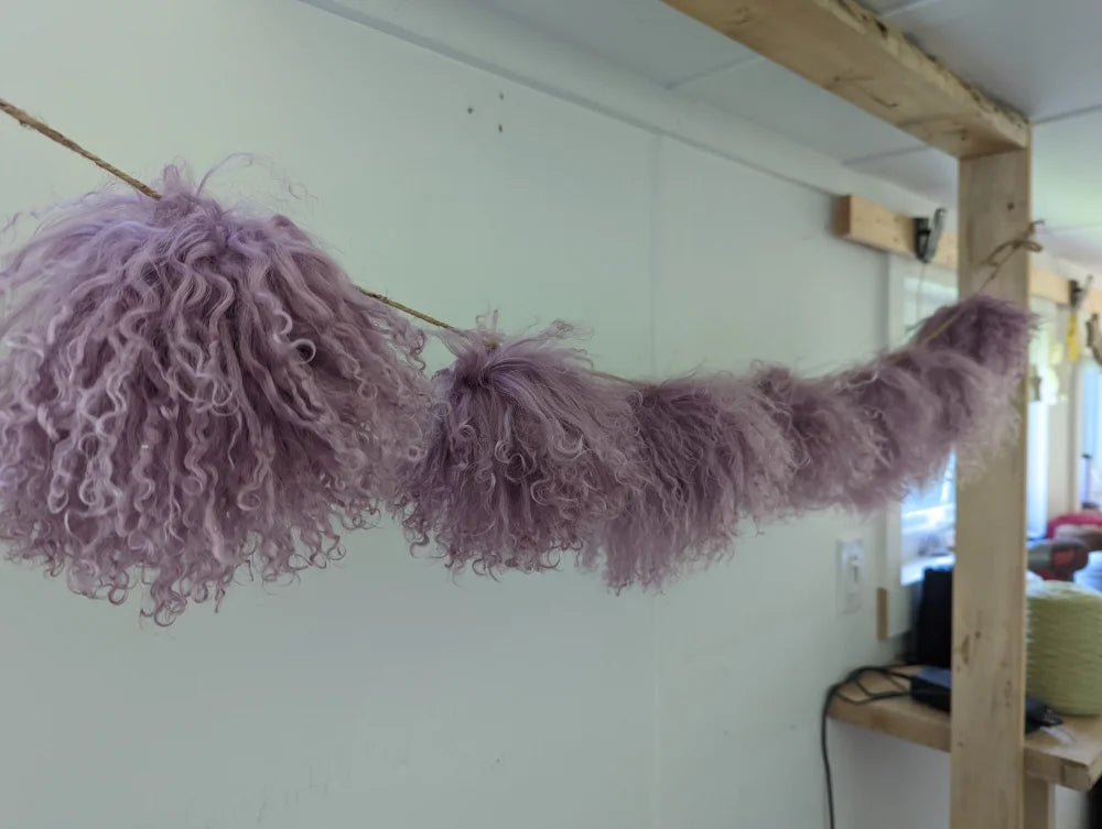 Medium pink sheepskin pom pom with lavender curly fur pillow