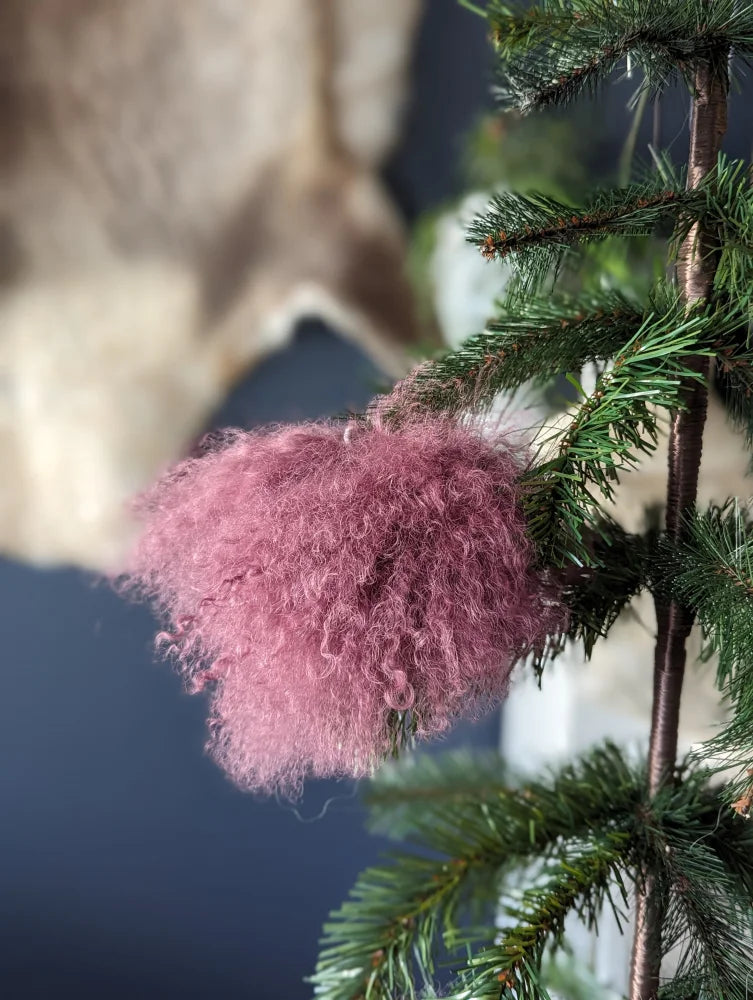 Medium pink sheepskin pom pom ornament on pine branch