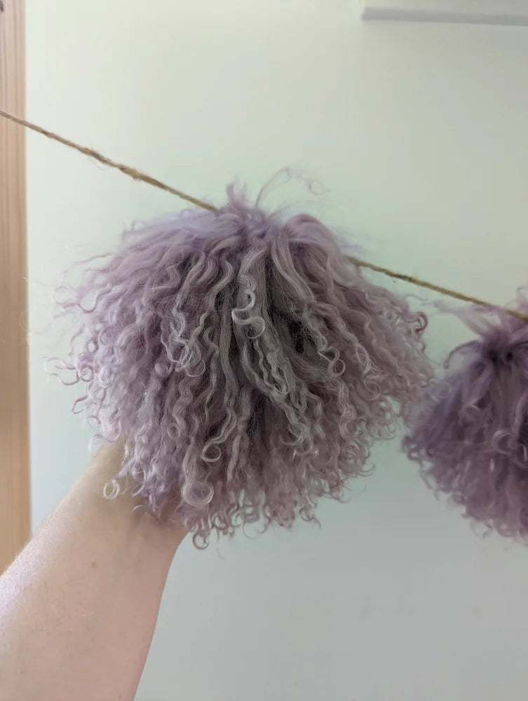 Medium pink sheepskin pom pom with lavender curly hair and metallic sheen
