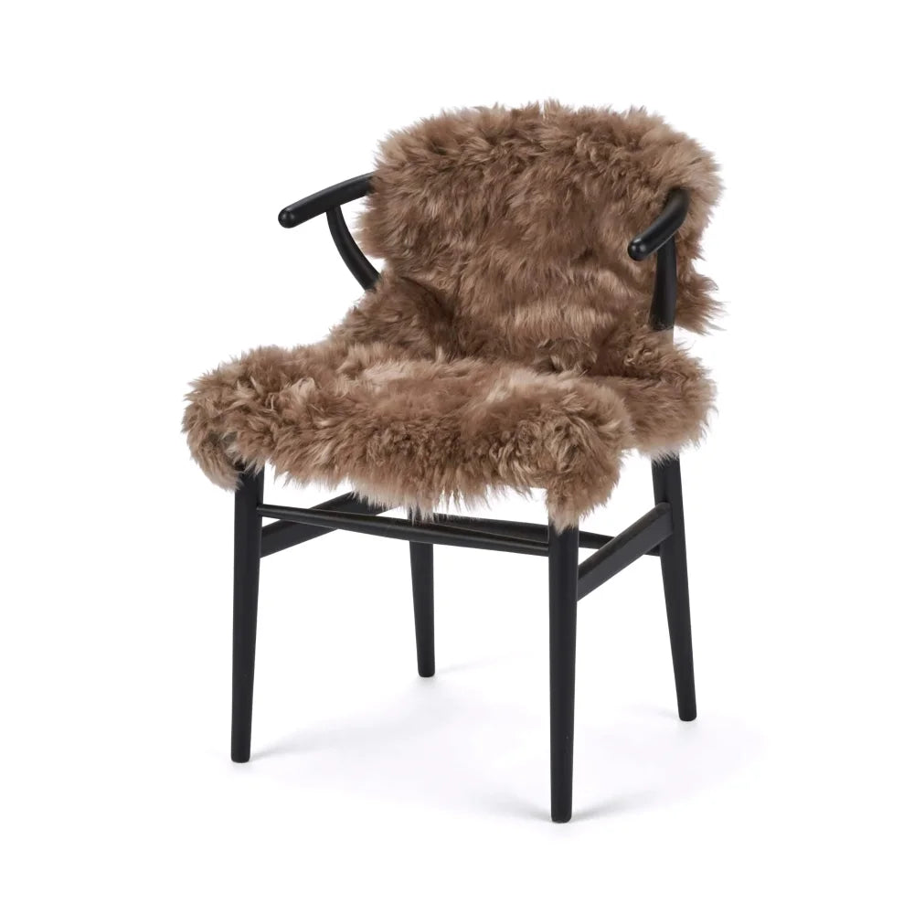 A cozy tan medium taupe merino sheepskin chair with sleek black frame made from dyed merino sheepskins meeting strict european standards