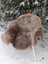 A cozy medium taupe merino sheepskin chair cover draped over a wicker chair in snowy outdoor setting