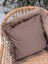 A cozy medium taupe merino sheepskin cushion with plush faux fur trim and cotton backs on a wicker chair