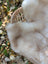 A cream-colored soft faux british isles sheepskin blanket draped over a woven wicker chair arm