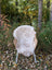 A cozy light beige british isles sheepskin rug draped over a wicker chair with white metal legs