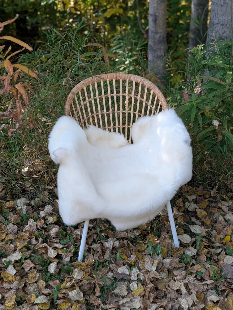White faux fur throw draped over a wicker chair with metal legs in a british isles sheepskin style